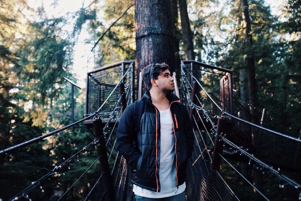 españoles Canadá chico moreno andando por un puente rodeado de vegetación